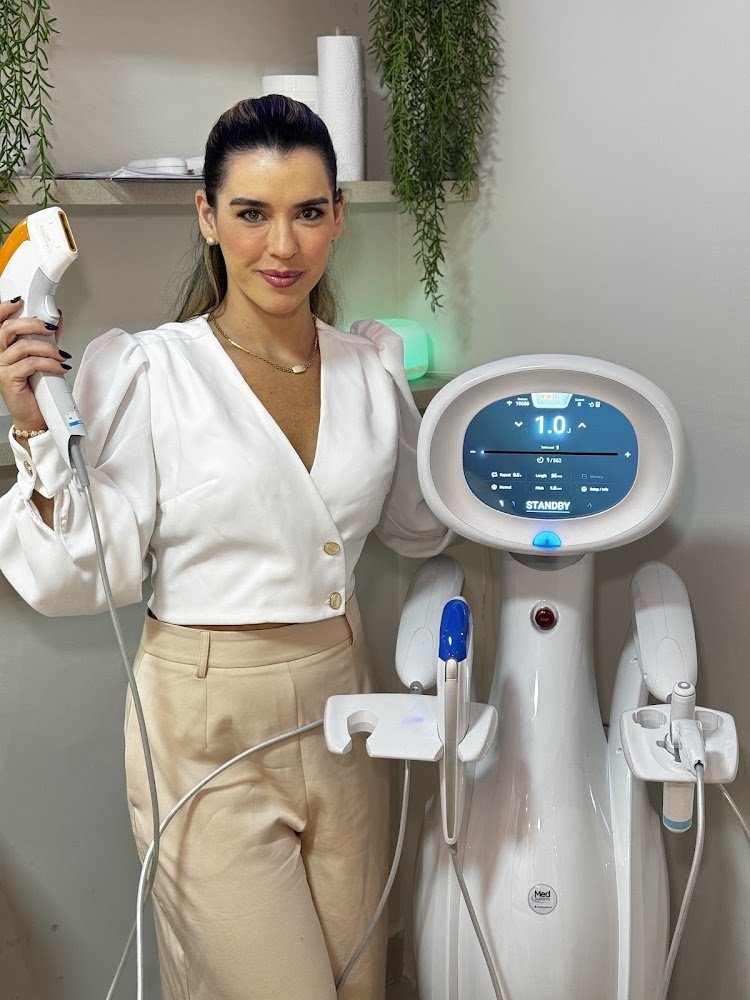 Dra. Ingrid Farias no consultório, ao lado de equipamento de estética avançada