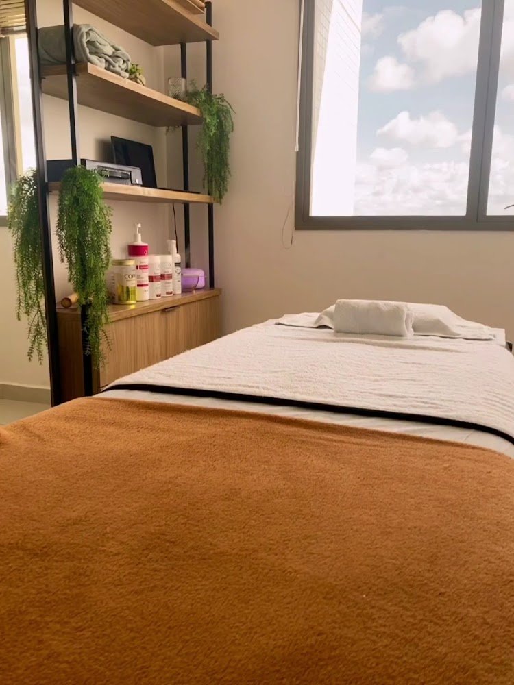 Sala de atendimento com maca caramelo, vegetação e janela com vista da cidade